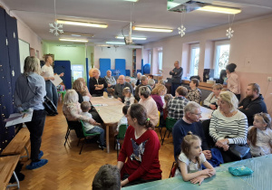 warsztaty plastyczne na sali gimnastycznej. dzieci razem z babciami i dziadkami wykonują ramki z lusterkami