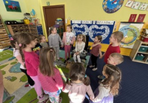 Dzieci ustawione w kole śpiewają "100 lat".