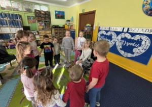 Dzieci ustawione w kole śpiewają "100 lat".