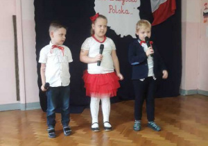 Troje dzieci - 2 chłopców i 1 dziewczynka recytują wiersz.