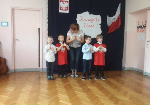 Czterech chłopców z naszego przedszkola recytuję wiersz, a pośrodku stoi Pani Małgosia