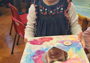 Dziewczynka prezentuje swoją pracę.