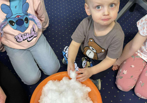 Dzieci siedzą na dywanie i poznają śnieg.