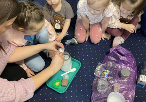 Dzieci siedzą na dywanie i eksperymentują ze śniegiem.