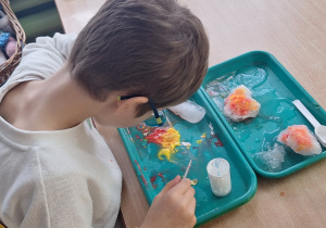 Chłopiec siedzi przy stole i eksperymentuje ze śniegiem.