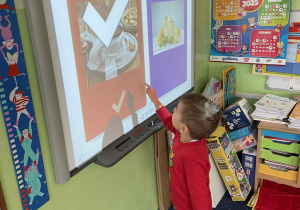 Dziecko wykonuje zadanie na tablicy interaktywnej.