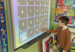 Chłopoiec wykonuje zadanie na tablicy multimedialnej.