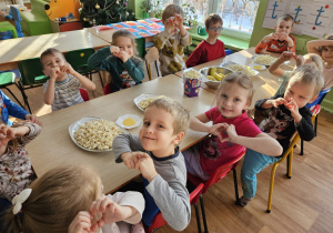 Dzieci siedzą przy stole na którym stoi popcorn.