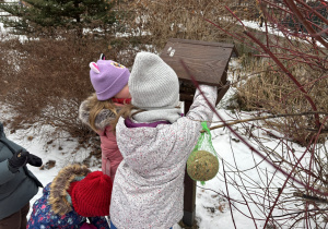 Dzieci wsypują nasionka do karmnika.