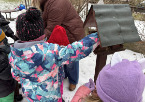 Dzieci wsypują nasionka do karmnika.