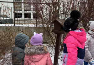 Dzieci wsypują nasionka do karmnika.