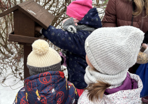 Dzieci wsypują nasionka do karmnika.