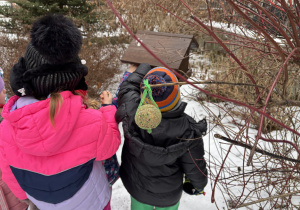 Dzieci wsypują nasionka do karmnika.