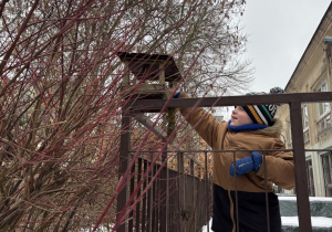 Dzieci wsypują nasionka do karmnika.