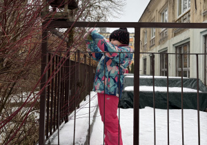 Dzieci wsypują nasionka do karmnika.