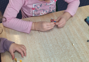 Dzieci siedzą przy stole i budują z klocków Lego.