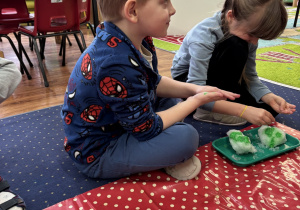 Dzieci siedzą na dywanie i badają śnieg.