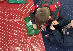 Dzieci siedzą na dywanie i badają śnieg.