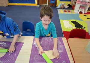 dzieci samodzielnie przy stolikach przygotowują pizzę