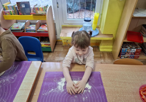 dzieci samodzielnie przy stolikach przygotowują pizzę