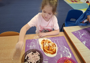 dzieci samodzielnie przy stolikach przygotowują pizzę