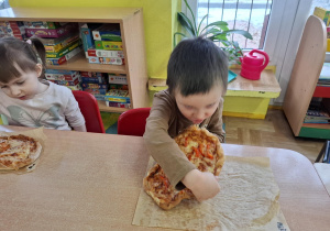 chłopiec zjada pizzę