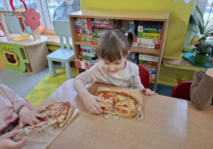 dziewczynka trzyma w rękach pizzę