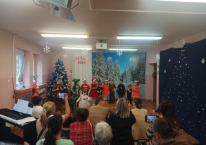 świateczny występ dzieci na sali gimnastycznej. dzieci mówią wiersze, śpiewają piosenki, rodzice oglądają występ.