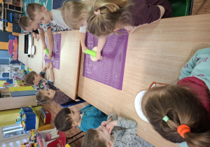 dzieci przy stolikach przygotowują pizzę