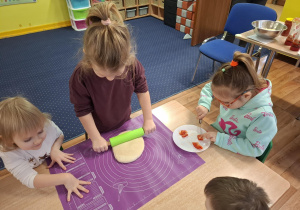 dzieci przy stolikach przygotowują pizzę