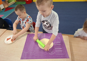 dzieci przy stolikach przygotowują pizzę