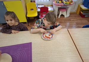 dzieci przy stolikach przygotowują pizzę