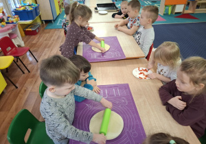 dzieci przy stolikach przygotowują pizzę