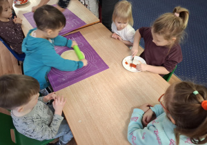 dzieci przy stolikach przygotowują pizzę