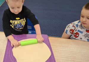 dzieci przy stolikach przygotowują pizzę