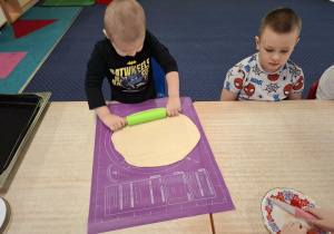 dzieci przy stolikach przygotowują pizzę