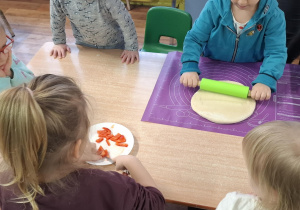 dzieci przy stolikach przygotowują pizzę