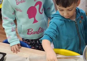 dzieci przy stolikach przygotowują pizzę