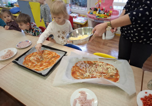 dzieci przy stolikach przygotowują pizzę