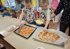 dzieci przy stolikach przygotowują pizzę