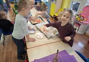 dzieci przy stolikach przygotowują pizzę