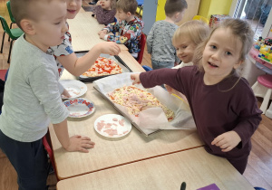dzieci przy stolikach przygotowują pizzę