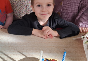 chłopiec świętuje urodziny, przed nim widać symboliczny tort