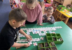 Dzieci przy stolikach kodują drogę ozobota.