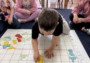 Dzieci na dywanie kodują z wykorzystaniem maty.