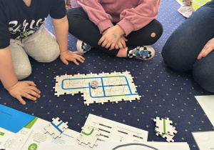 Dzieci przy stolikach kodują drogę ozobota.