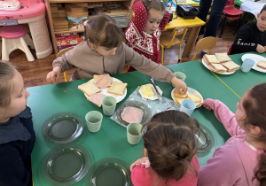 Dziewczynka siedzi przy stole i przygotowuje tosty.