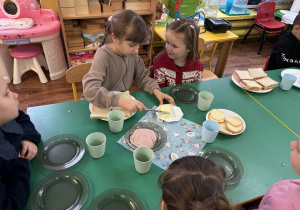 Dziewczynka siedzi przy stole i przygotowuje tosty.