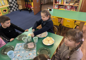 Dziewczynka siedzi przy stole i przygotowuje tosty.