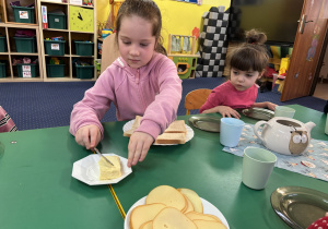 Dziewczynka siedzi przy stole i przygotowuje tosty.